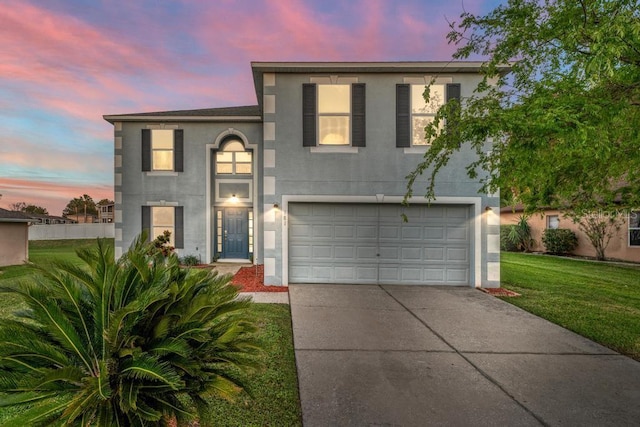 traditional home with stucco siding, a front yard, an attached garage, and driveway