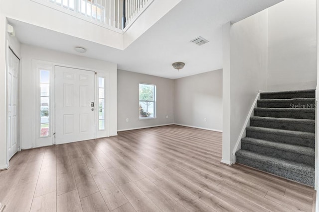 entrance foyer with stairway, light wood-style flooring, visible vents, and baseboards