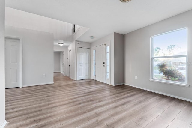 unfurnished living room with light wood-style flooring and baseboards