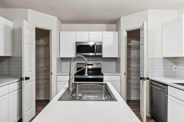 kitchen with dark wood finished floors, light countertops, white cabinets, and appliances with stainless steel finishes