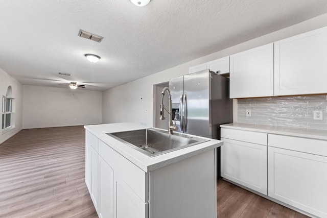 kitchen with visible vents, light wood finished floors, a kitchen island, a sink, and stainless steel refrigerator with ice dispenser