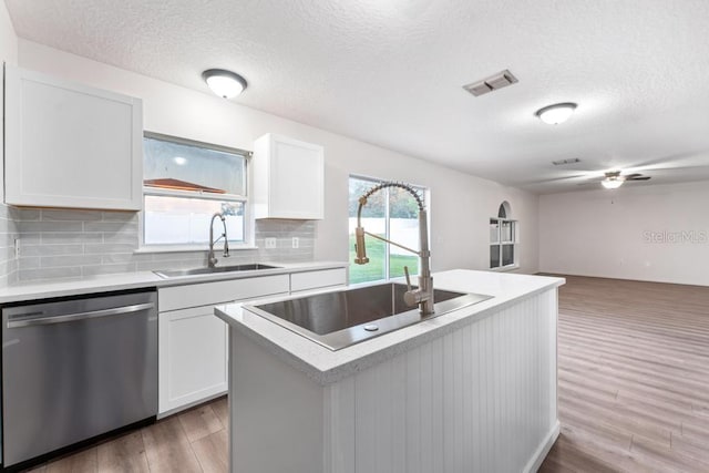 kitchen featuring a sink, wood finished floors, visible vents, and stainless steel dishwasher