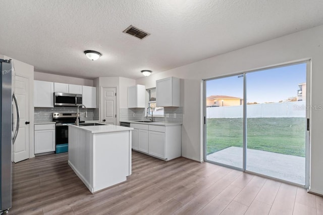 kitchen with visible vents, stainless steel appliances, an island with sink, and a sink