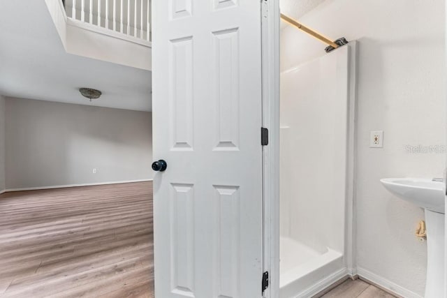 bathroom with baseboards, wood finished floors, and a stall shower