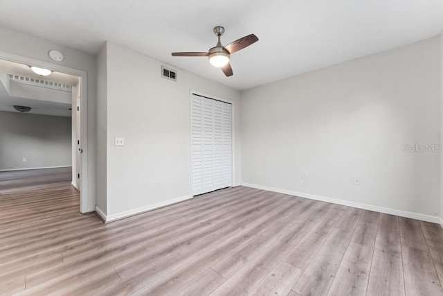 unfurnished bedroom featuring visible vents, ceiling fan, baseboards, wood finished floors, and a closet