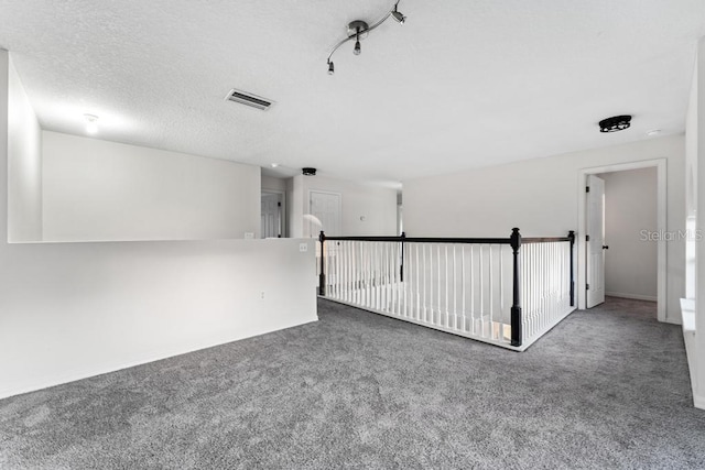 empty room featuring carpet flooring, visible vents, and a textured ceiling