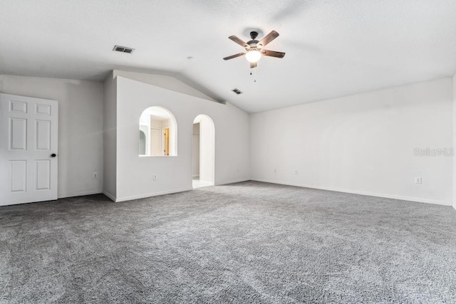 carpeted empty room with arched walkways, visible vents, ceiling fan, and vaulted ceiling