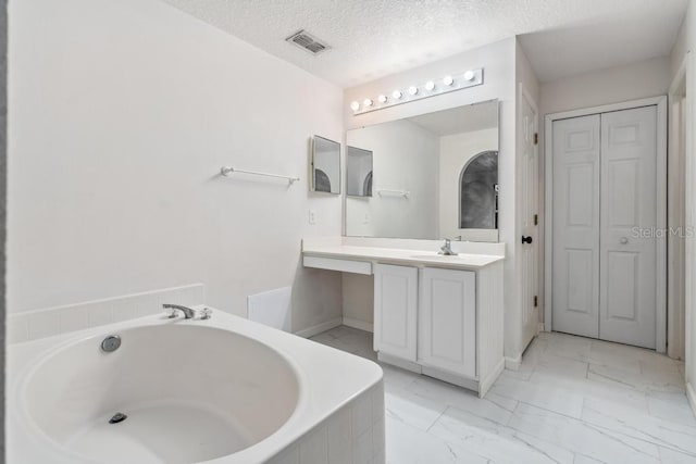 full bath featuring vanity, visible vents, a textured ceiling, a garden tub, and marble finish floor