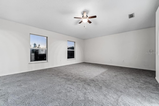 carpeted empty room with visible vents and a ceiling fan