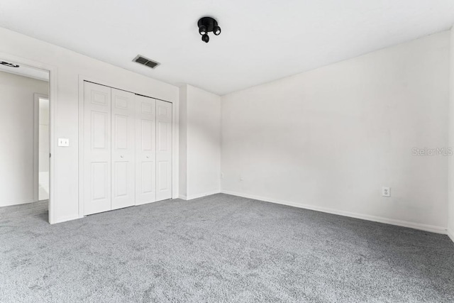 unfurnished bedroom featuring carpet, visible vents, a closet, and baseboards