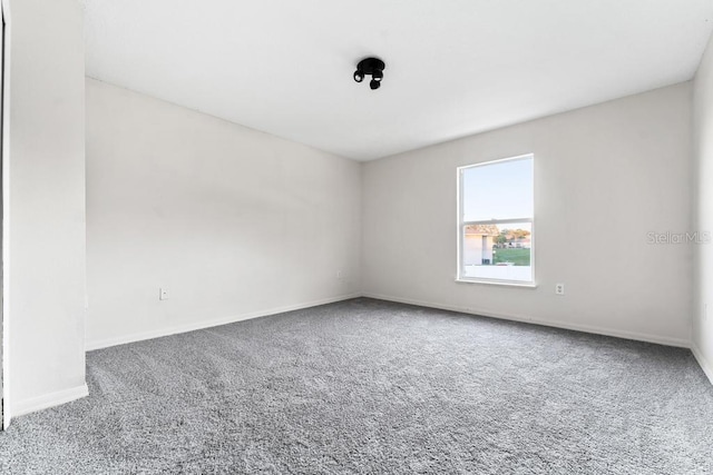 carpeted spare room featuring baseboards