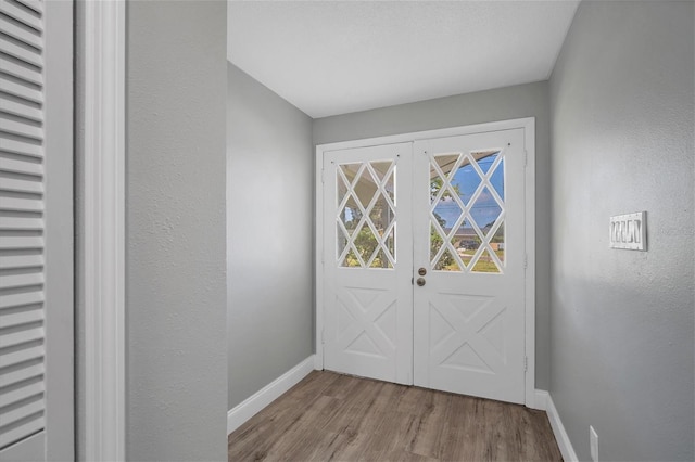 entryway featuring a textured wall, baseboards, and wood finished floors