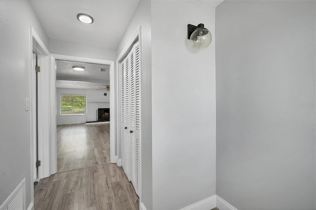 corridor with visible vents, baseboards, and wood finished floors