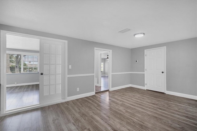 empty room featuring visible vents, baseboards, and wood finished floors