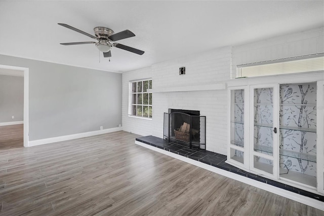 unfurnished living room with a ceiling fan, wood finished floors, a fireplace, and baseboards