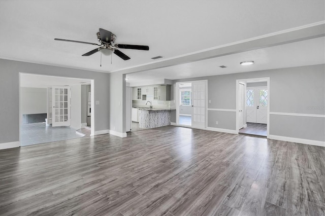 unfurnished living room with a sink, visible vents, baseboards, and dark wood-type flooring