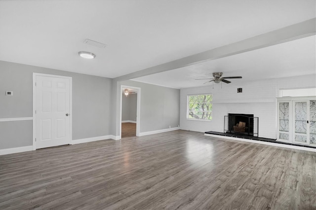 unfurnished living room with wood finished floors, a fireplace, baseboards, and ceiling fan