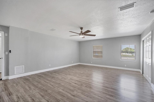 unfurnished room featuring visible vents, baseboards, and wood finished floors