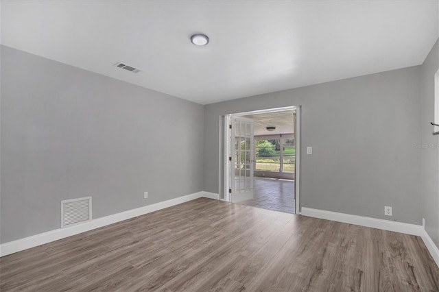 unfurnished room with visible vents, baseboards, and wood finished floors