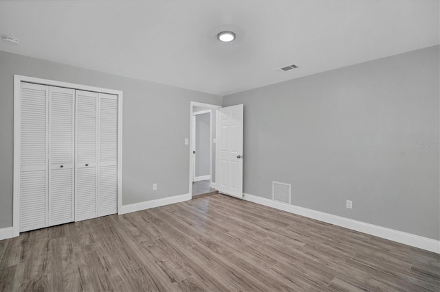 unfurnished bedroom with visible vents, baseboards, and wood finished floors