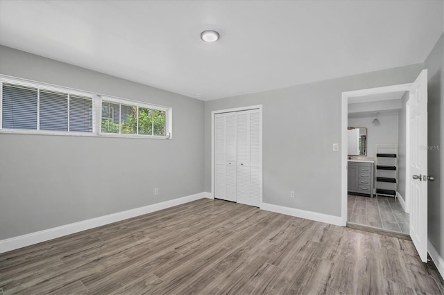 unfurnished bedroom featuring a closet, baseboards, and wood finished floors