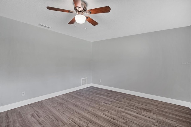 empty room with ceiling fan, visible vents, baseboards, and wood finished floors