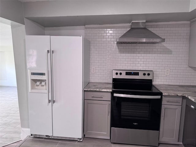 kitchen with tasteful backsplash, gray cabinetry, wall chimney range hood, stainless steel electric range, and white refrigerator with ice dispenser