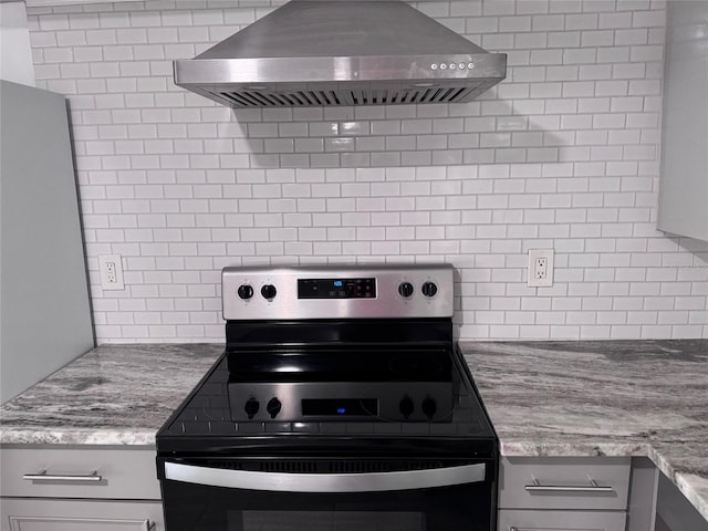 kitchen with light stone counters, black / electric stove, gray cabinets, decorative backsplash, and extractor fan