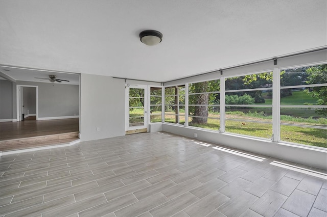 interior space with a sunroom, a ceiling fan, a wealth of natural light, and wood tiled floor