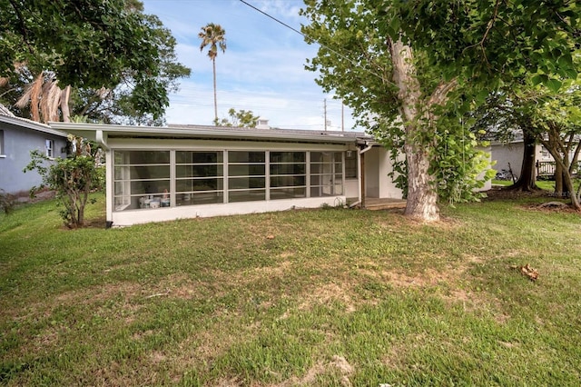 rear view of house with a lawn and a sunroom