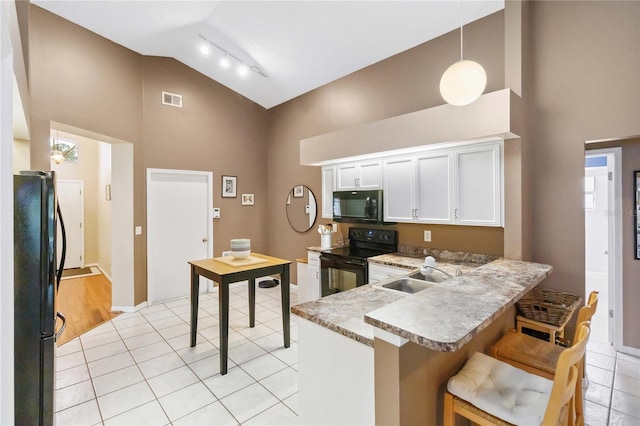 kitchen featuring visible vents, light tile patterned floors, white cabinets, black appliances, and a sink