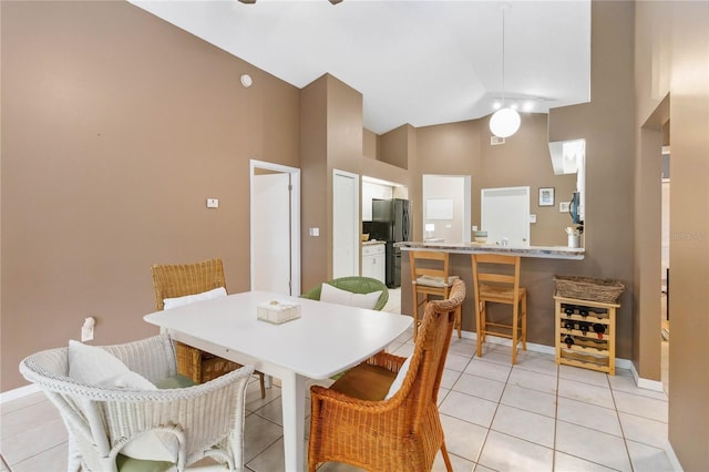 dining space featuring light tile patterned flooring, baseboards, and high vaulted ceiling