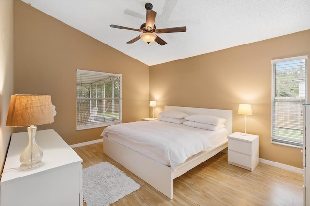 bedroom with lofted ceiling, light wood-style flooring, a ceiling fan, and baseboards