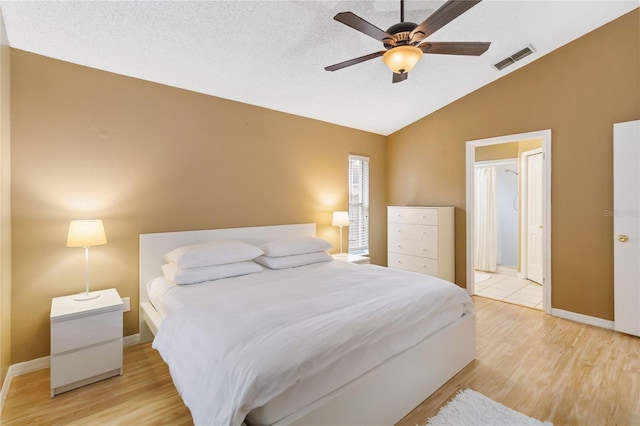 bedroom featuring vaulted ceiling, light wood-style flooring, baseboards, and visible vents