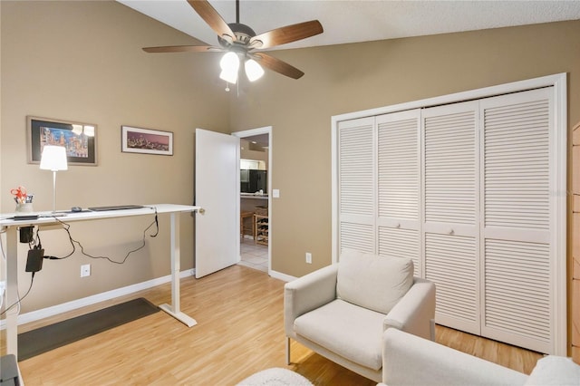 living area featuring light wood finished floors, baseboards, lofted ceiling, and a ceiling fan