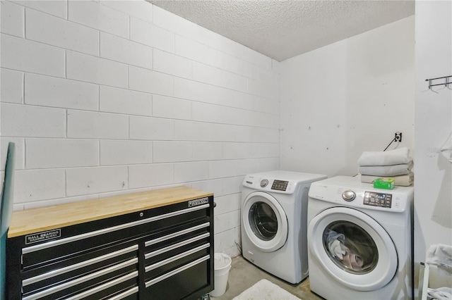 washroom featuring washing machine and clothes dryer, laundry area, a textured ceiling, and concrete block wall