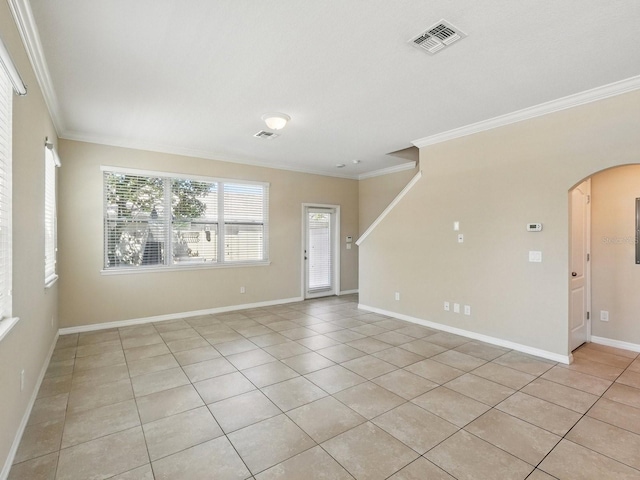 unfurnished room with visible vents, baseboards, ornamental molding, light tile patterned floors, and arched walkways