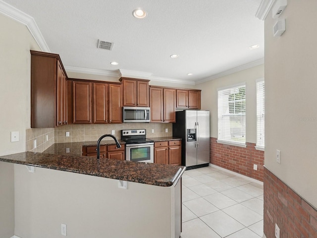 kitchen with visible vents, brick wall, a peninsula, stainless steel appliances, and a sink