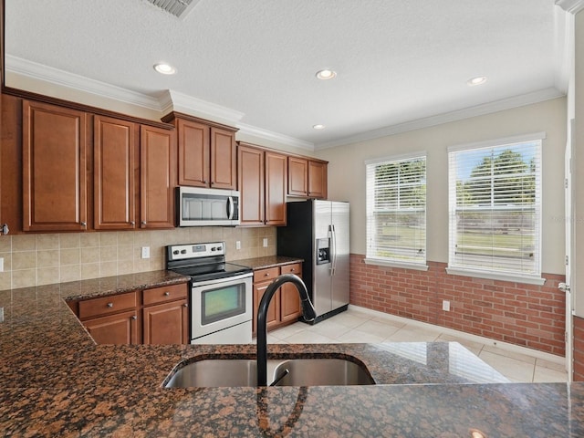 kitchen featuring a sink, light tile patterned floors, brown cabinetry, and stainless steel appliances