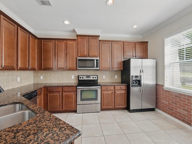 kitchen featuring light tile patterned flooring, brown cabinetry, appliances with stainless steel finishes, and a sink