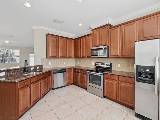 kitchen featuring dark stone countertops, visible vents, a sink, appliances with stainless steel finishes, and brown cabinets