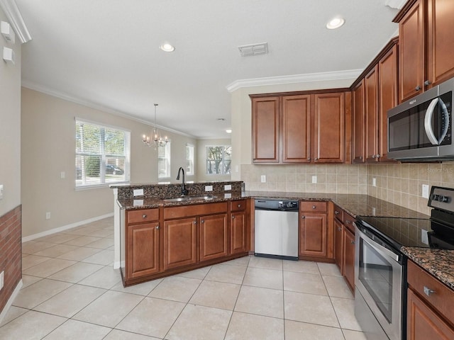 kitchen with visible vents, a peninsula, a sink, stainless steel appliances, and a notable chandelier