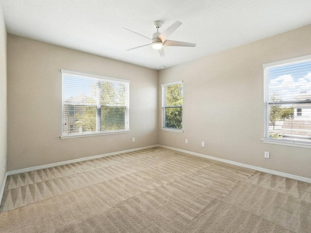 carpeted spare room featuring baseboards and ceiling fan