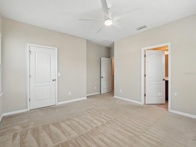 unfurnished bedroom featuring ceiling fan, baseboards, visible vents, and light carpet