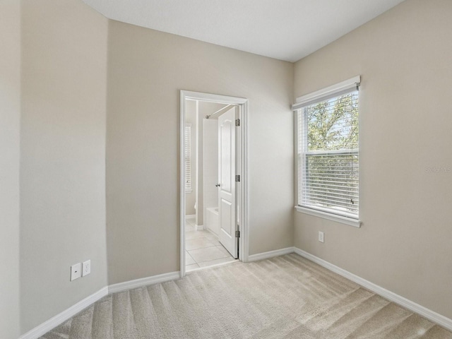 unfurnished bedroom featuring carpet flooring, ensuite bathroom, and baseboards