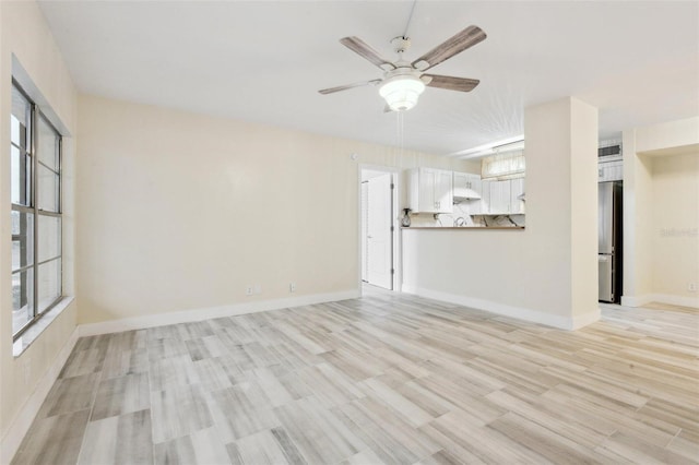 unfurnished living room with light wood-style flooring, a ceiling fan, and baseboards