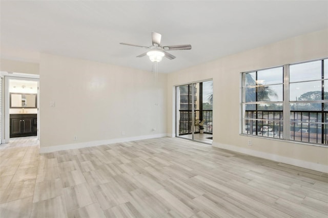 spare room featuring a ceiling fan, baseboards, and light wood finished floors