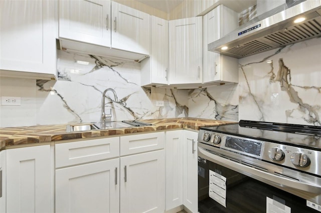 kitchen with a sink, exhaust hood, white cabinets, stainless steel electric range oven, and wooden counters