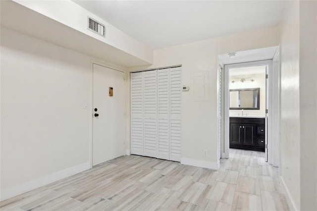 spare room with light wood-style flooring, baseboards, visible vents, and a sink