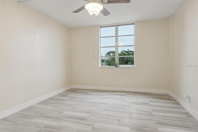 spare room featuring ceiling fan, light wood-style flooring, and baseboards